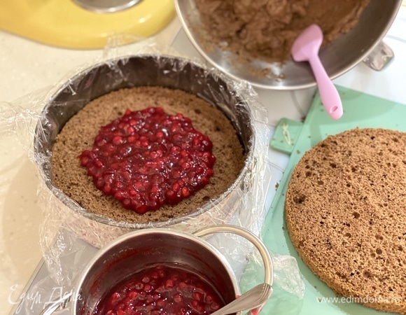 Соберем торт. Форму выстелить пищевой пленкой. На дно выложить 1 корж, по центру — половину брусничной начинки.