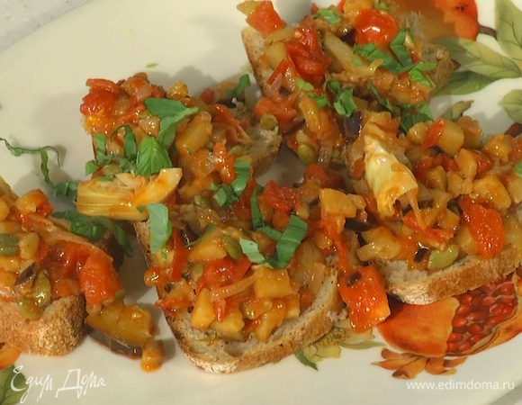 Хлеб нарезать, подсушить с двух сторон на сковороде-гриль, затем смазать оставшимся оливковым маслом, разложить на него готовую капонату и посыпать базиликом.