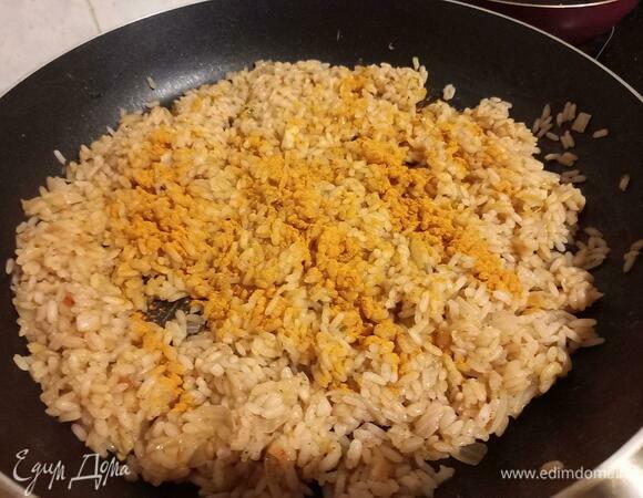Добавляем в рис специи: соль, черный перец, куркуму. Аккуратно с солью — ранее мы уже добавили соленый соевый соус. Куркума нужна для того, чтобы придать рису приятный желтый оттенок. Перемешиваем и жарим до полного выпаривания воды.