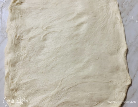 Посыпаем мукой поверхность стола и выкладываем на него тесто. Не сильно обминая тесто, растягиваем его руками в пласт.