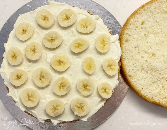 Бисквит разрезать на 2 части. Намазать первый корж кремом, сверху выложить нарезанные бананы и дно второго коржа тоже смазать кремом. Накрыть первый корж. Сверху намазать остатки крема и украсить по желанию.