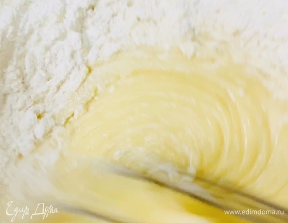 Добавляем половину просеянной муки, разрыхлитель и ванилин. Замешиваем тесто ложкой.