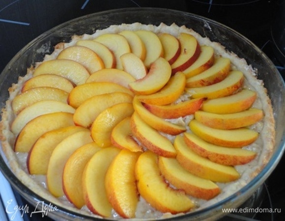 Выложите крем на корж, разровняйте лопаткой и по всей поверхности разложите дольки персика.