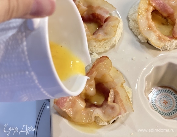 Уложить бекон в корзинки из хлеба вдоль стенки. Влить яйцо. По желанию посыпать сыром. Запекать в духовке до желаемой готовности яйца.