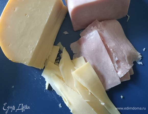 Тонко нарезать сыр и ветчину.