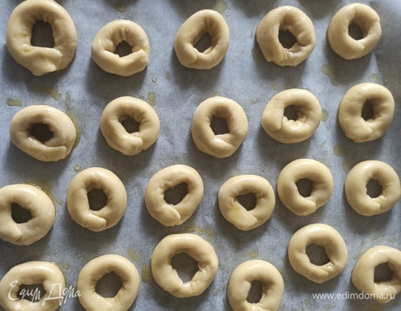 Противень застелить пергаментной бумагой, выложить сушки. Сверху смазать оливковым маслом. При желании можно посыпать приправой для пиццы, паприкой или кунжутом.