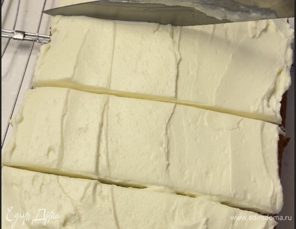 Для крема масло взбить с сахарной пудрой добела. Добавить сливочный сыр. Снова взбить. Распределить крем поверх коржа. Нарезать на квадратики.