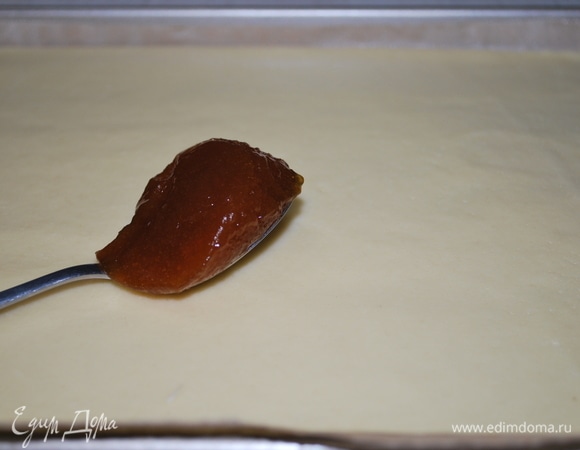 Через 40 минут достать тесто из холодильника и раскатать его в тонкий пласт примерно (5–6 мл). Тесто смазать тонким слоем мармелада или повидла (у меня сливовый мармелад).