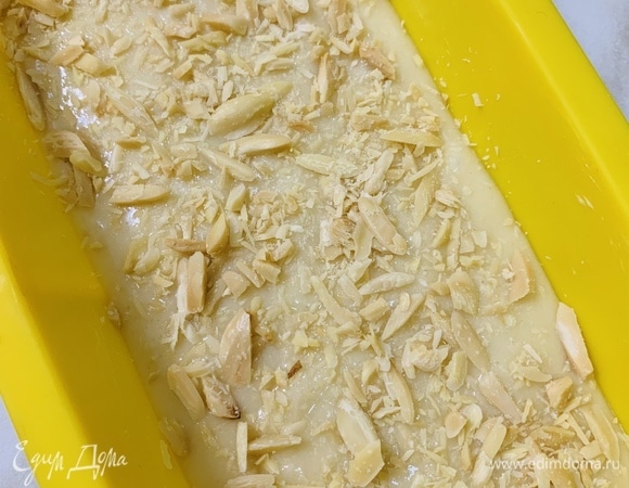 Форму для кекса смазываем сливочным маслом и слегка припыляем мукой. Выкладываем половину теста. Посыпаем половиной миндаля.