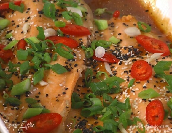 Готовую рыбу посыпать белым и черным кунжутом, чесноком, перцем чили и зеленым луком.