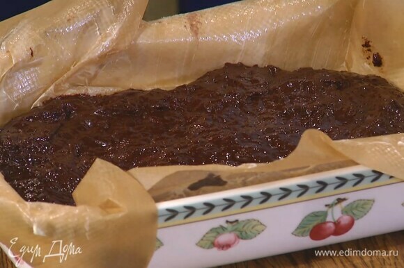 Керамическую форму выстелить бумагой для выпечки, смазанной оставшимся сливочным маслом, выложить шоколадную массу и разровнять ее.