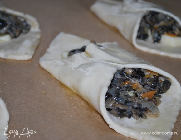 На середину квадрата выложила сыр, а сверху сыра — грибную икру (у меня грибы обжарены с луком и морковью). Хорошо защипнула края и смазала сиропом (подойдет любой сироп без ягод). Поставила выпекаться в духовку при температуре 180°C на 20 минут.