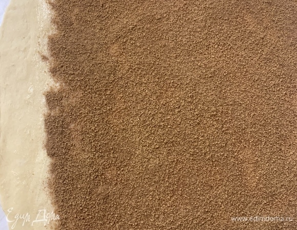 Смешиваем корицу с сахаром. Равномерно посыпаем смесью покрытое маслом тесто и равномерно распределяем по всей площади, кроме чистого края. Слегка придавливая руками, утрамбовываем сахарную смесь.