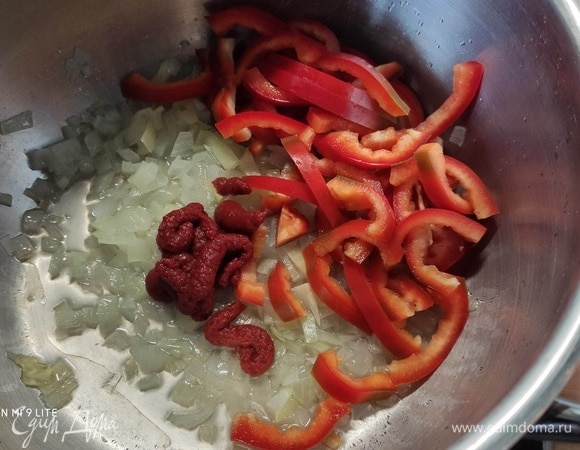 В кастрюле разогреть масло, пассеровать мелко нарезанный лук до прозрачности, добавить нарезанный перец и томатную пасту, обжарить.