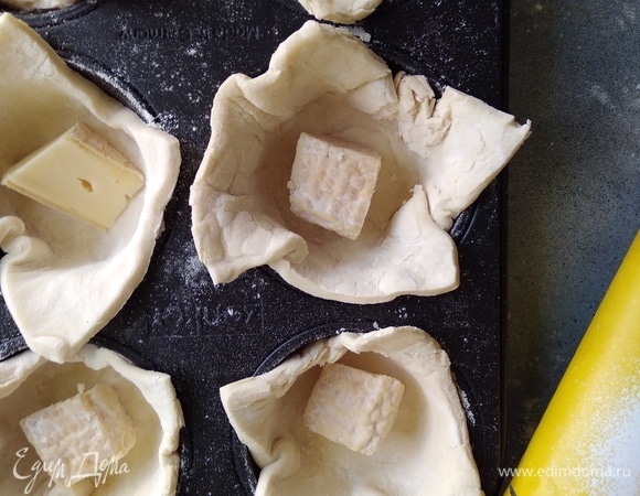 Сыр бри нарезать кусочками. Положить по кусочку в каждую корзинку. По желанию можно добавить нарезанный чеснок.