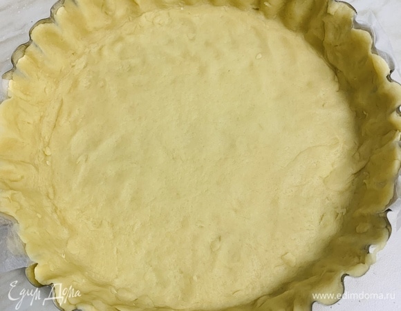 Перекладываем тесто в форму. Края можно оставить как есть или аккуратно подрезать ножом. Совет: если у формы неразъемное дно, вырежете из пергамента две широкие полоски чуть длиннее диаметра формы и выстелите ими дно, а тесто положите сверху. Так будет легко доставать готовый тарт из формы.