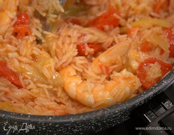 Помидоры нарезать дольками, добавить вместе с креветками к рису, все посолить и перемешать, увеличить огонь и прогревать еще несколько минут до готовности креветок.