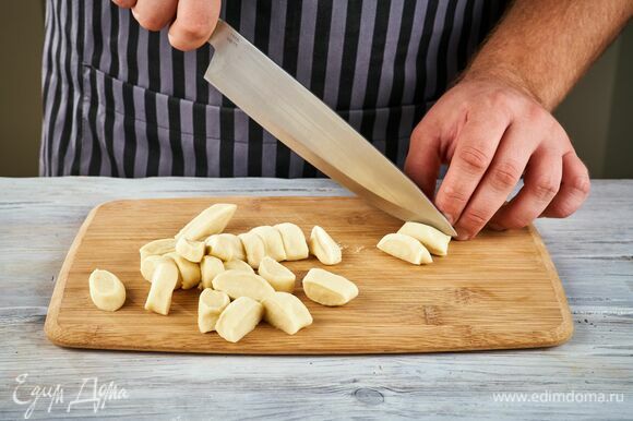 На рабочей поверхности скатайте из теста колбаски толщиной 2 см и нарежьте их на кусочки шириной 2 см.