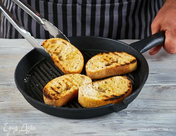 Чиабатту нарежьте кусочками толщиной 1 см, сбрызните оливковым маслом каждый кусочек и подсушите на сковороде-гриль.