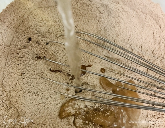 К мучной смеси добавляем воду комнатной температуры (можно заменить соком, кофе или молоком) и растительное масло. Перемешиваем венчиком до однородности.