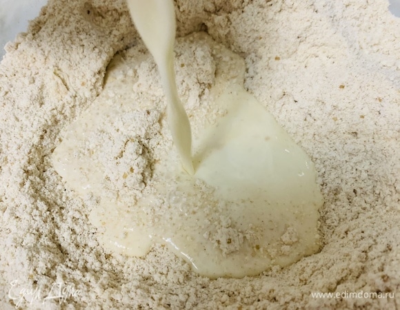 Молочно-яичную смесь делим пополам. Часть заливаем к мучной смеси с добавками и перемешиваем до однородности. Тесто месить не нужно. Оно будет довольно липким.
