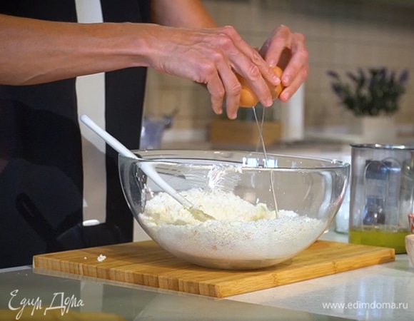 Приготовить тесто: кокосовую стружку и предварительно размягченное сливочное масло выложить в глубокую посуду и вымешать до однородной консистенции, добавить сахарную пудру, ванильный экстракт, желток, 2 яйца и вымешать тесто сначала лопаткой, затем руками.