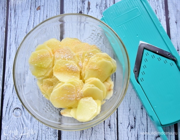 Картофель очистить от кожуры и нарезать тонкими слайсами при помощи специальной терки. Посолить, добавить чесночный порошок и растительное масло. Перемешать.