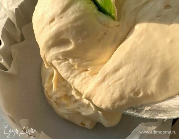 Форму застелите пергаментом и выложите половину теста.