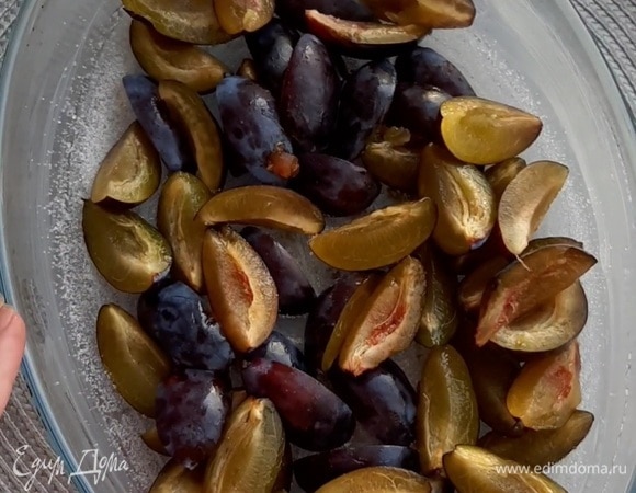 Сливы нарезать на четвертинки и выложить на дно формы. Форму смазать сливочным маслом и посыпать сахаром.