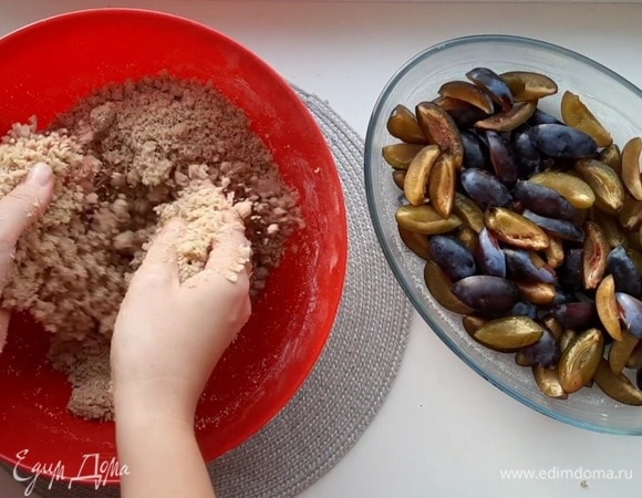 Мягкое сливочное масло соединить с сахаром, ванильным сахаром и мукой. Руками перетереть в крошку. Засыпать крошкой сливы и убрать в разогретую до 180°C духовку на 30–35 минут.
