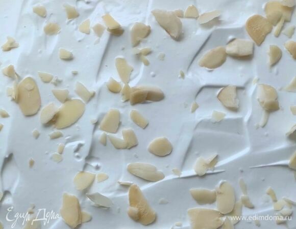 Равномерно распределите меренгу на силиконовом коврике, получится слой толщиной 1–1,2 см. Сверху посыпьте миндальными лепестками. Выпекайте меренгу в разогретой духовке при 150°С около 23–25 минут, до первых трещинок на поверхности.