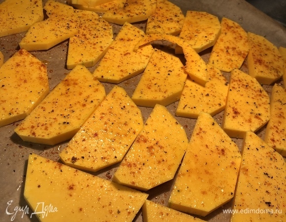 Духовку разогреть до температуры 220°C. Тыкву (желательно использовать сладкие сорта, например, баттернат) почистить, нарезать ломтиками, выложить на застеленный пергаментом противень, посыпать специями (соль, перец, различные травы), сбрызнуть оливковым маслом и запечь в течение 20–30 минут, до румяного состояния.