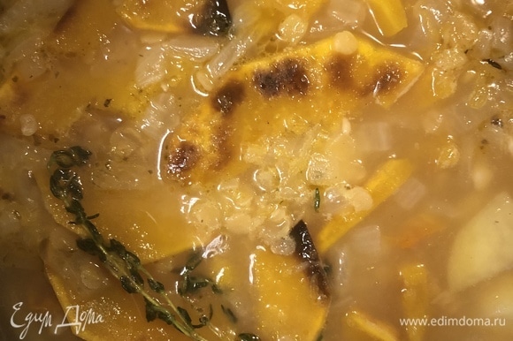 Добавить запеченную тыкву, веточку тимьяна и варить суп на среднем огне до готовности овощей и чечевицы.