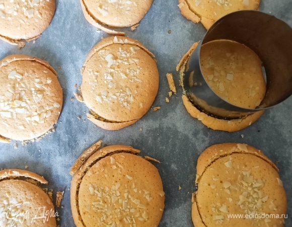 Противень застелить пергаментной бумагой, с помощью кондитерского мешка выдавить тесто, формируя небольшое круглое печенье (11–12 штук). Сверху посыпать рубленым миндалем и отправить в предварительно разогретую до 170°C духовку на 8–10 минут. Затем круглой формой диаметром 6 см еще теплое печенье подогнать под один размер.