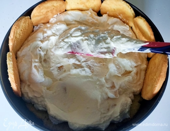 На дно формы уложить бисквит. Пропитать. В центр выложить немного крема, затем по кругу поставить печенье, постепенно распределить крем по всей поверхности бисквита, таким способом мы фиксирует печенье. Когда все печенье зафиксировано, выложить оставшийся крем.