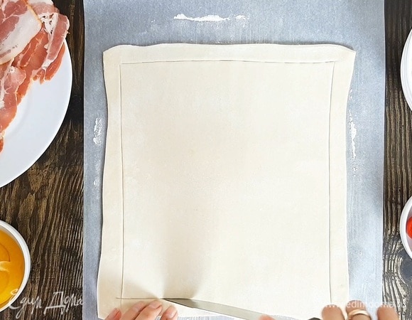 Сыр натираем на крупной терке. Помидоры черри разрезаем пополам. Перец нарезаем кольцами. Тесто немного раскатываем и делаем неглубокие надрезы вдоль всего края, отступив около 1,5 см.