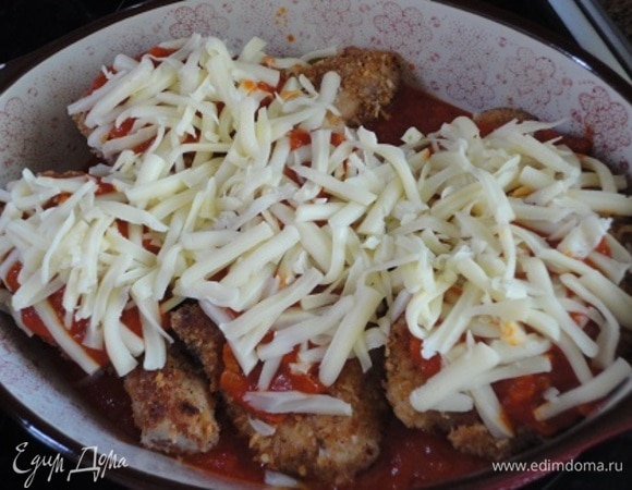 На каждый кусочек курицы выложить небольшое количество томатного соуса. Посыпать тертой на крупной терке полутвердой моцареллой. Не надо заливать толстым слоем соуса всю курицу.