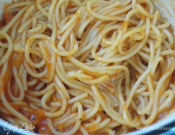 Пока курочка запекается, отварите спагетти в большом количестве подсоленной воды. Слить воду и переложить спагетти к оставшемуся томатному соусу. Перемешать.