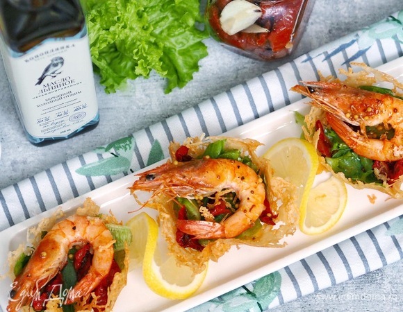 Листья салата (в идеале рукола, у меня фриллис сегодня) промыть, просушить и мелко нарезать или руками порвать, добавить заправку и перемешать. Вяленые томаты нарезать тонкими дольками. Собираем корзиночки: нижний слой — салат с заправкой, сверху — креветки и дольки помидоров. Если осталась заправка, можно сверху чуть полить. Подавать сразу, пока корзиночки хрустящие.