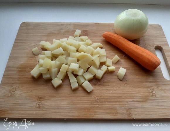 Поставить кастрюлю с водой на огонь. Картофель нарезать кубиками. Когда вода закипит, добавить картофель. Снова довести до кипения.