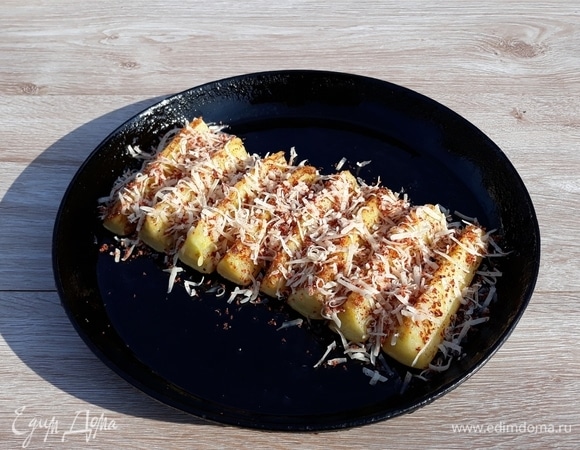 Посыпать обжаренные кабачковые ломтики сыром и специями. Поставить сковороду с кабачками в духовой шкаф, разогретый до 200°C, на 5 минут, чтобы сыр расплавился.