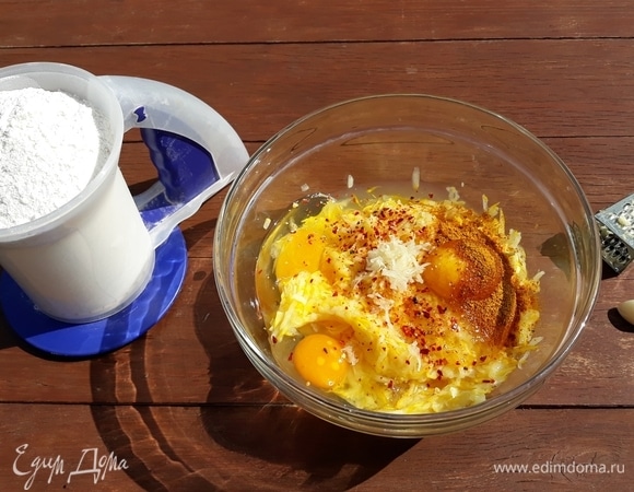 В емкость с кабачками разбить яйца, добавить тертый на мелкой терке чеснок, карри, черный перец и чили для остроты, немного зелени укропа и петрушки. Все перемешать и постепенно добавить муку. Еще раз перемешать до однородной массы.