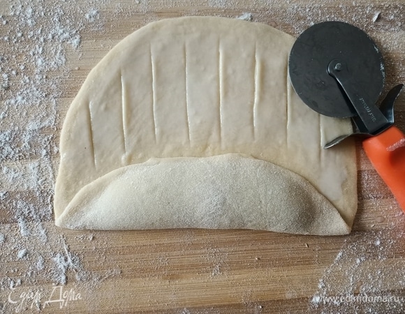 Затем смазать молоком и с помощью ножа для пиццы сделать разрезы на тесте на расстоянии 1 см и не доходя до края 1 см.