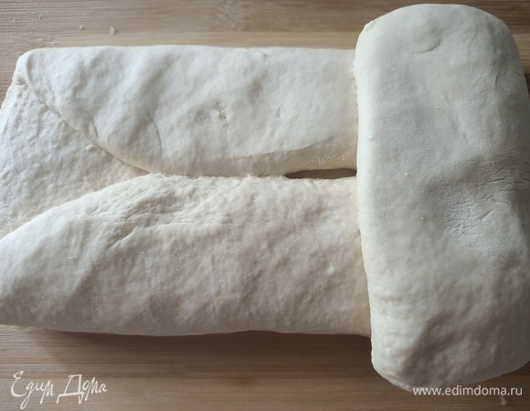 Выложить тесто на посыпанную мукой поверхность, распределить руками и сложить квадратом, как лист бумаги. Затем необходимо взять концы и соединить их в центре, придавая тесту форму шара. Выложить в глубокую миску швом вниз, накрыть пищевой пленкой и поставить в теплое место на два часа.