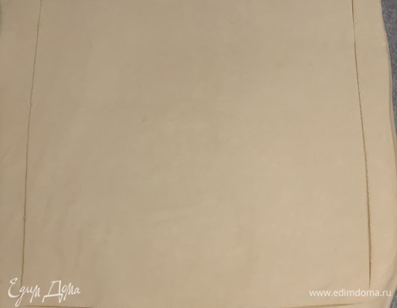 На пергаменте раскатываем тесто в прямоугольник и надрезаем, оставляя с каждой стороны по 1–1,5 см.