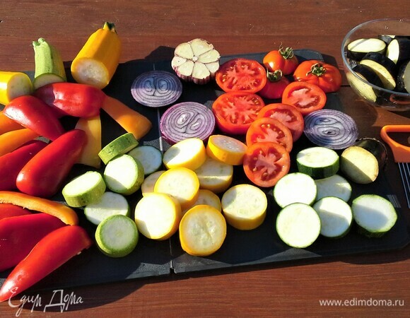 Пробежимся по огороду, соберем все нужные ингредиенты для приготовления блюда. Овощи промыть. Кабачки, баклажаны, лук, помидоры нарезать кольцами. Баклажаны 20 минут подержать в растворе соли, чтобы убрать горечь. Перцы очистить от семян и нарезать, чеснок разрезать поперек головки. Овощи сбрызнуть маслом. 