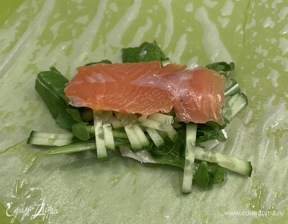 Кладем рисовую бумагу в глубокую тарелку с водой и ждем, когда она размокнет. Огурцы мелко нарезаем, рвем руколу.