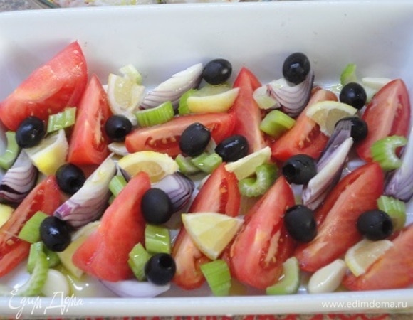 Включить духовку для разогрева до 220°C, а в это время подготовить овощи: чеснок очистить, лук и помидоры нарезать дольками, лимон — ломтиками, сельдерей — кусочками. Все овощи вместе с маслинами выложить в форму, полить 1 ложкой оливкового масла и запекать в духовке 15–20 минут.