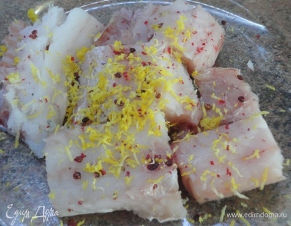 Тем временем филе рыбы нарезать порционными кусочками, натереть солью, цедрой лимона, посыпать растолченным розовым перцем и сбрызнуть оставшимся оливковым маслом.