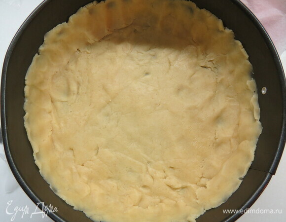 Форму диаметром 18 см застилаем бумагой для выпечки. Выкладываем на дно раскатанное тесто, формируем бортики и убираем в холодильник на полчаса.